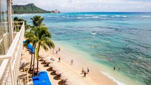A beach with clear turquoise water, palm trees, and a view of a mountain in the background. - Luxe Life on the Ocean’s Edge w/Wraparound Lanai, Kitchen–Waikīkī Shore 500 (HONOLULU)