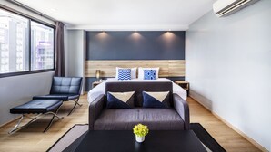 A modern hotel room with a bed, a sofa, a recliner, and a small table with a plant. - Narra Hotel (Bangkok)