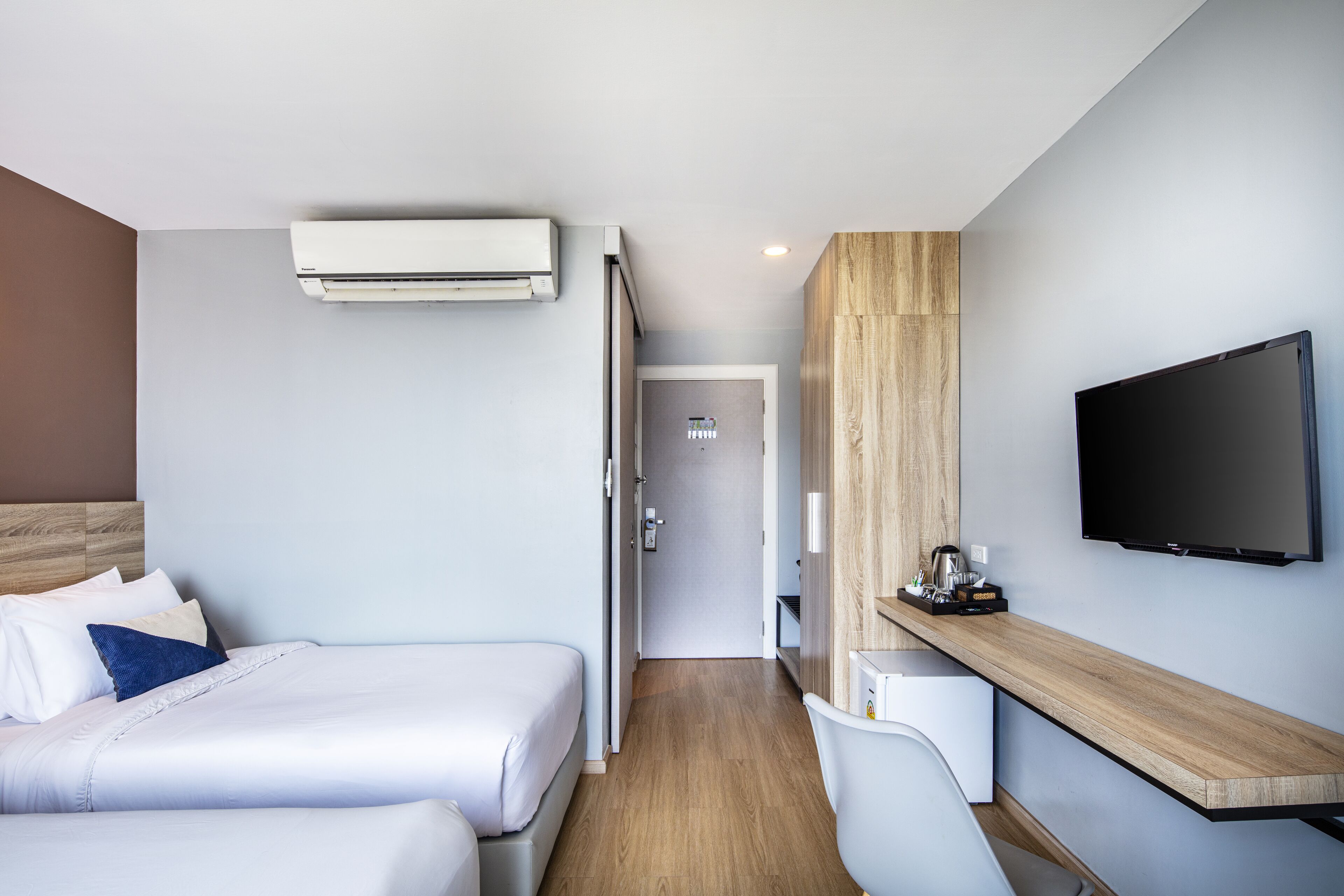 Una habitación de hotel moderna con dos camas, un escritorio, un televisor de pantalla plana y un equipo de aire acondicionado.