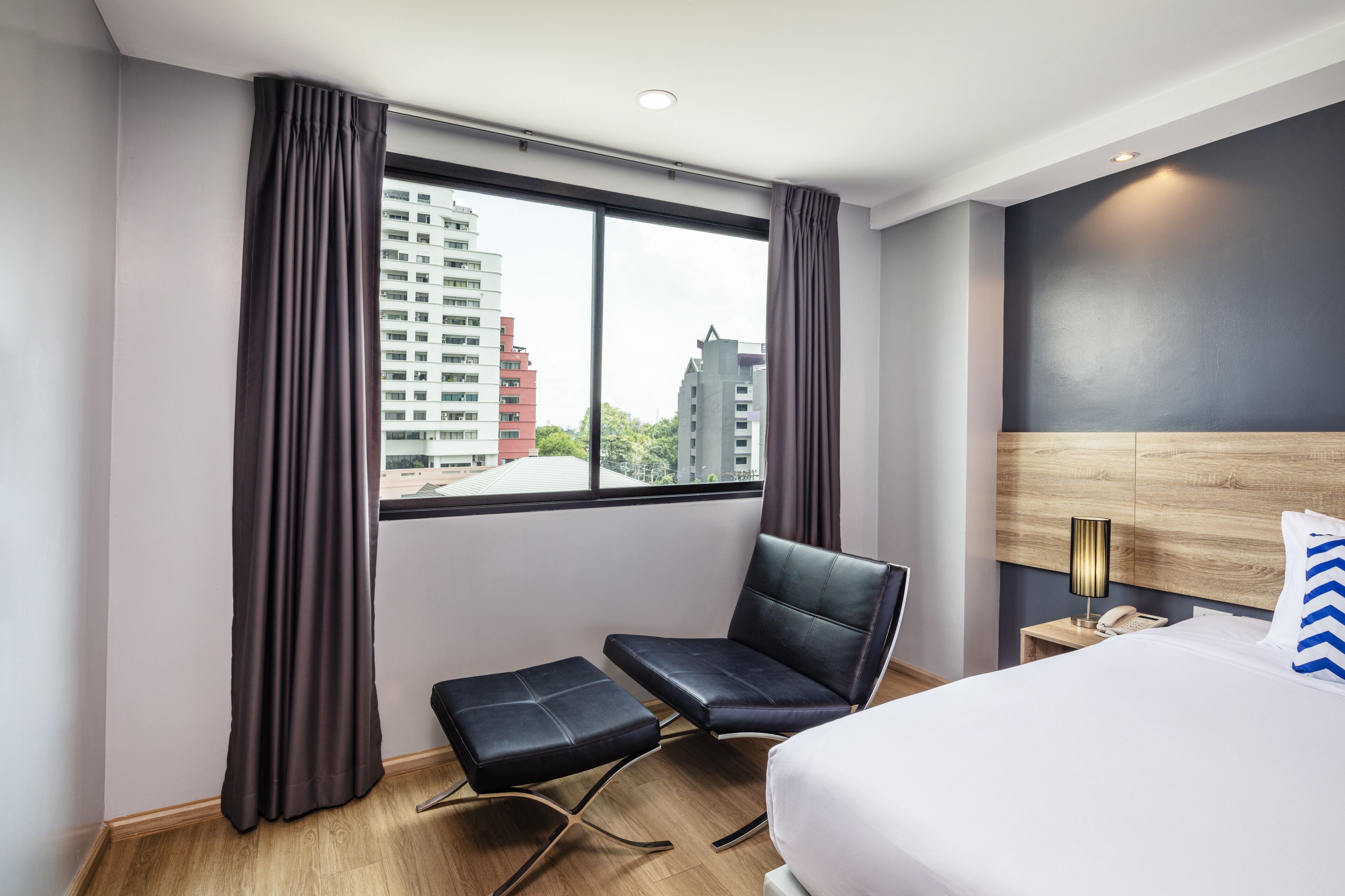 Una habitación de hotel con un ventanal grande, una cama, una silla y una mesita.