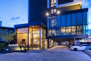Ein modernes Hotel mit Glasfassade, Außenbereich zum Sitzen und einer Tiefgarage.
