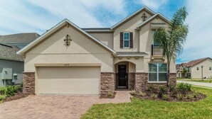 A two-story house with a garage, stone accents, and a small tree in the front yard. - Spanish Sunset - Private Pool/Spa & 24/7 Support (Davenport)