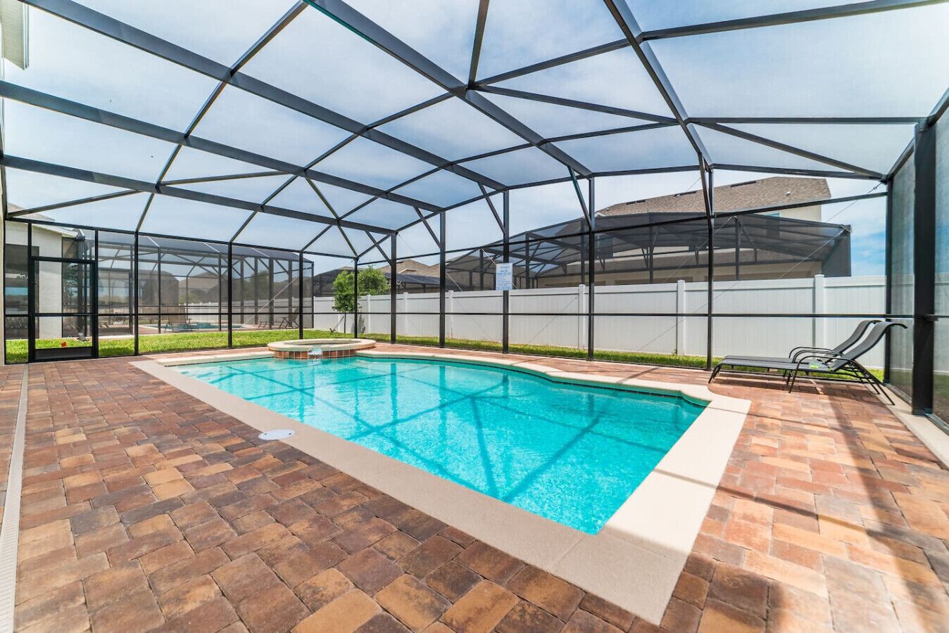 Una piscina techada con un solárium de ladrillo y sillas de descanso.