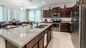 A modern kitchen with granite countertops, stainless steel appliances, and dark wood cabinets. - Spanish Sunset - Private Pool/Spa & 24/7 Support (Davenport)