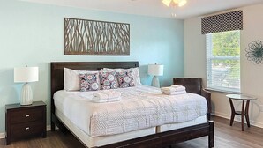 A bedroom with a bed, two bedside tables, a ceiling fan, a window with blinds, and a decorative wall piece. - Spanish Sunset - Private Pool/Spa & 24/7 Support (Davenport)