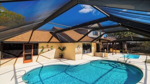 Una piscina techada con estructura de techo, un pequeño jardín y una puerta que da a un edificio.