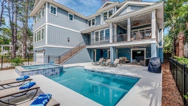 Uma casa de dois andares com piscina, área de estar externa e escada que leva ao andar superior.