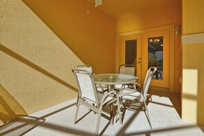 A dining area with a round table and four chairs, a door with glass panels, and a textured wall. - Disney Escape | Private Pool | Resort Amenities | Sleeps 10 (Kissimmee)