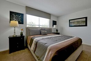 A bedroom with a bed, two nightstands, a window with blinds, and two wall-mounted lamps. - Private Pool, Waterview, No Rear Neighbors | Paradise Palms Resort (Kissimmee)