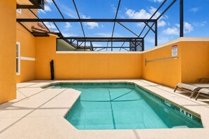 A swimming pool with a safety sign, a sunshade, and a view of the sky through a metal structure.
