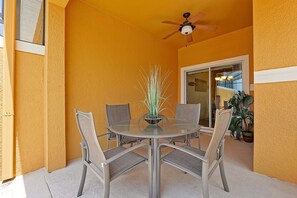 A round glass table with four chairs, a ceiling fan, and a potted plant in the center. - Private Pool, Waterview, No Rear Neighbors | Paradise Palms Resort (Kissimmee)