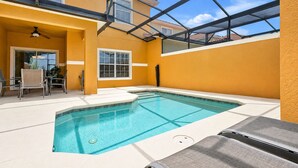 A swimming pool with a glass ceiling, surrounded by a yellow wall, and a lounge chair in the foreground. - Private Pool, Waterview, No Rear Neighbors | Paradise Palms Resort (Kissimmee)