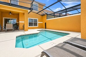 A swimming pool with a glass ceiling, surrounded by a yellow wall, and a lounge chair in the foreground. - Private Pool, Waterview, No Rear Neighbors | Paradise Palms Resort (Kissimmee)
