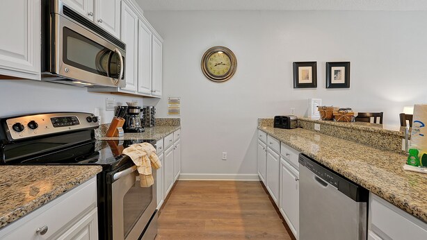 A kitchen with white cabinets, a stainless steel microwave, a stove, and a dishwasher. - Private Pool, Waterview, No Rear Neighbors | Paradise Palms Resort (Kissimmee)