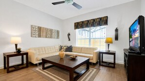 A living room with a sofa, coffee table, TV, and decorative items. - Private Pool, Waterview, No Rear Neighbors | Paradise Palms Resort (Kissimmee)