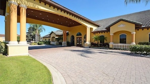 A yellow building with a covered entrance and a paved driveway. - Private Pool, Waterview, No Rear Neighbors | Paradise Palms Resort (Kissimmee)