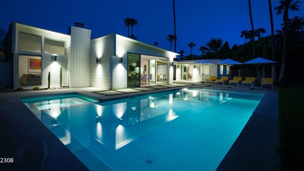 A modern house with a swimming pool, large windows, and outdoor seating.