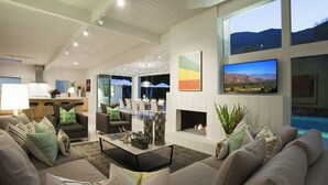 A modern living room with a fireplace, comfortable seating, and a large TV.