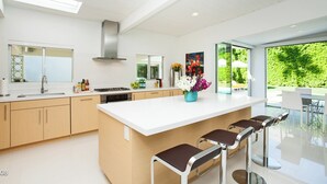 A modern kitchen with a large island, bar stools, and a view of the outdoors.
