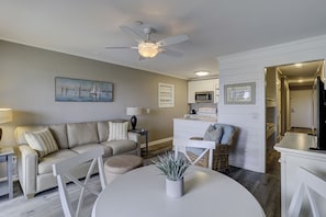Ein modernes Wohnzimmer mit einem beigefarbenen Sofa, einem weißen Couchtisch und einem Deckenventilator.