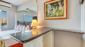 Ett modernt hotellrum med en böjd marmorskiva som bordsskiva, en säng med vita sängkläder, ett stort fönster med utsikt över staden och en tavla på väggen.