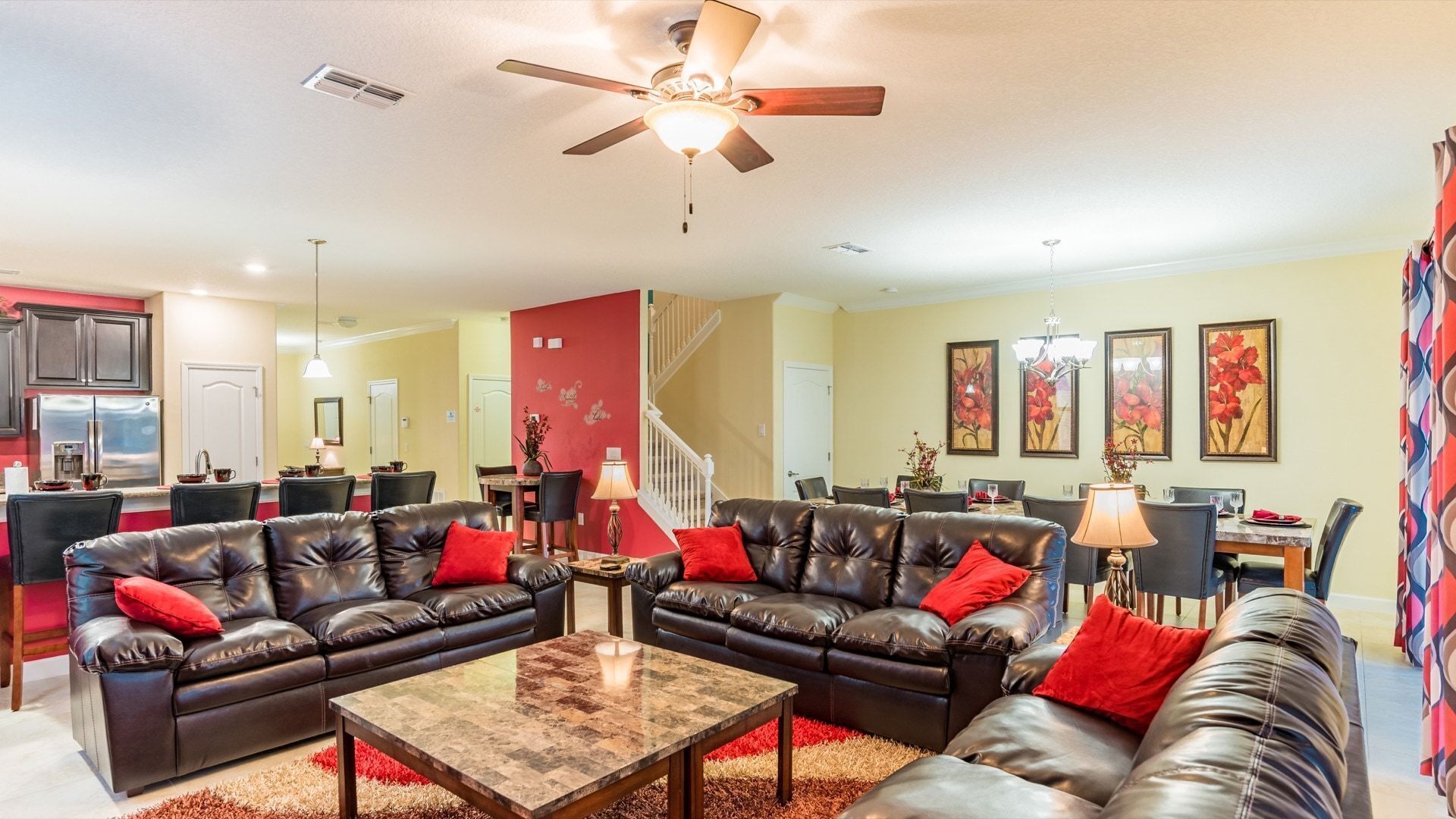 A spacious living room with leather sofas, a coffee table, and a dining area with a staircase.