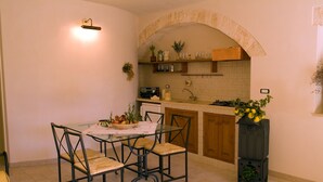Une cuisine compacte comprenant une table à manger, des chaises, une cuisinière encastrée et un petit réfrigérateur.