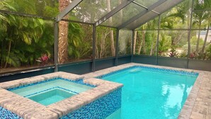 Ein Pool mit Glasveranda, umgeben von tropischer Vegetation.
