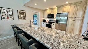 Eine moderne Küche mit Granit-Arbeitsplatten, Edelstahlgeräten und einer großen Kochinsel mit Barhocker.