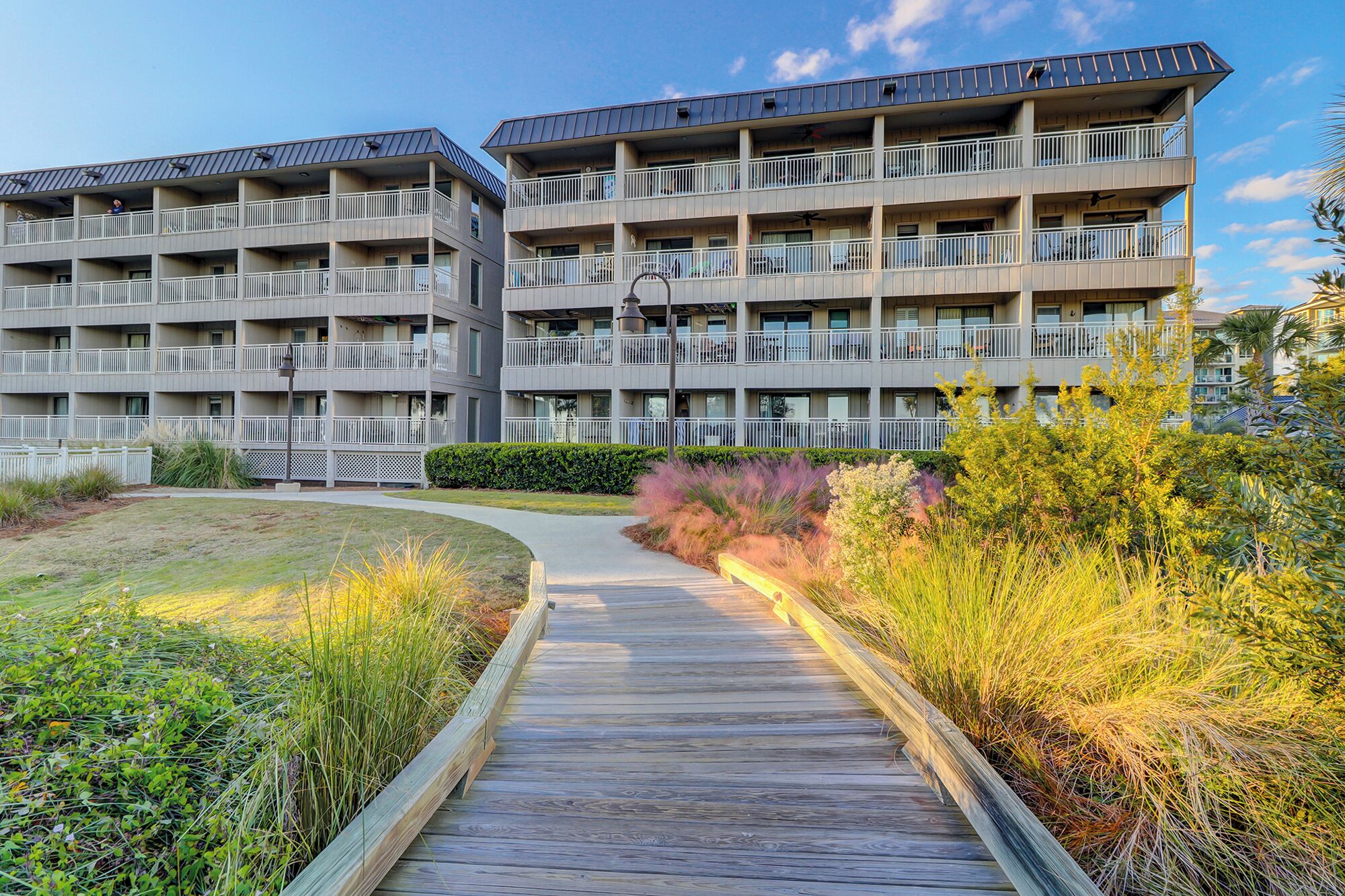 A multi-story hotel with balconies, a wooden boardwalk, and landscaped areas.