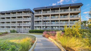 A multi-story hotel with balconies, a wooden boardwalk, and landscaped areas. - Breathtaking Ocean Views and Heated Pool! (Hilton Head Island)