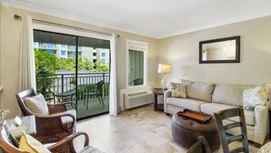 A living room with a sofa, chairs, a table, a balcony with a view of buildings and greenery, and a radiator. - Breathtaking Ocean Views and Heated Pool! (Hilton Head Island)