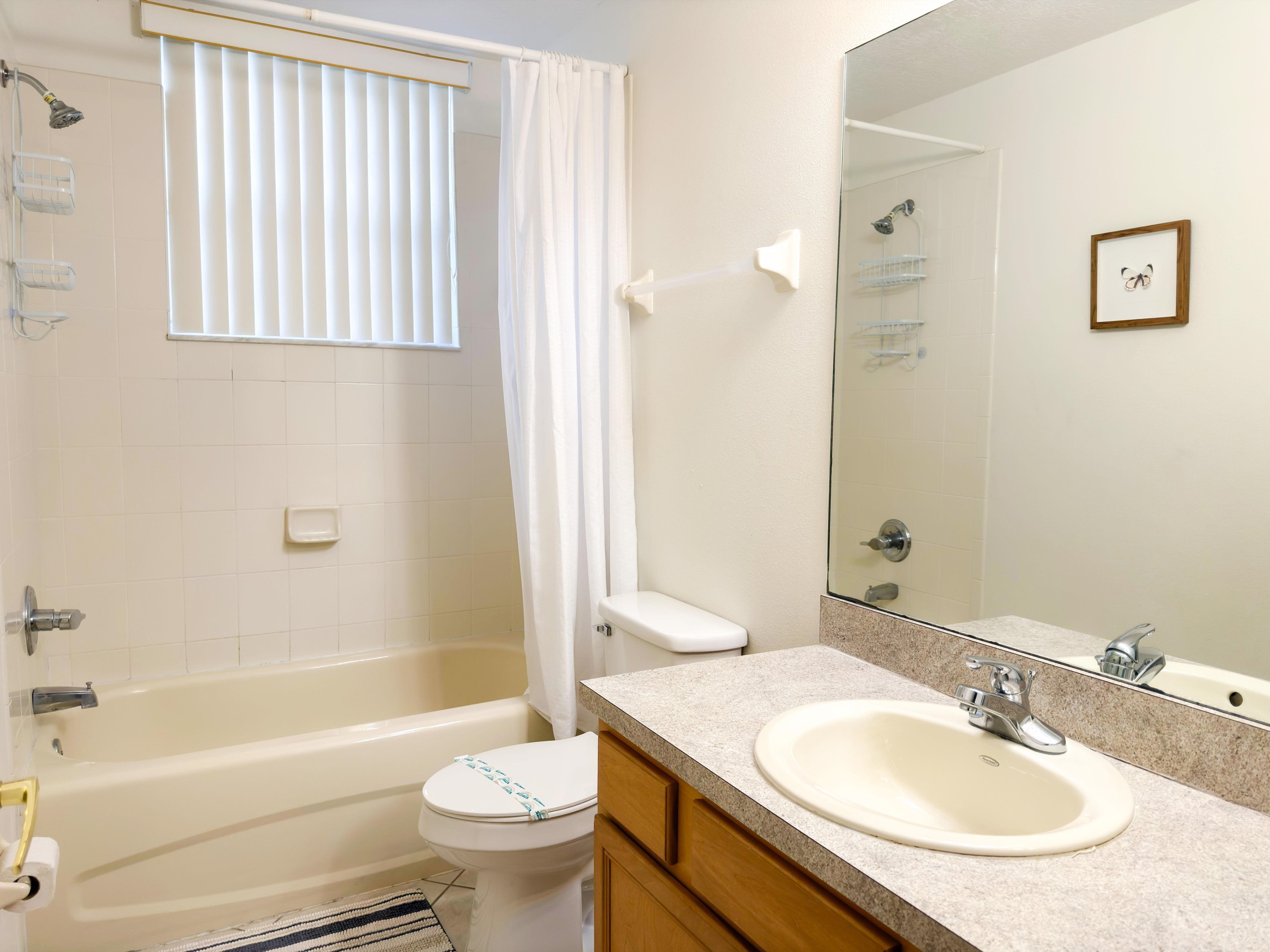 A bathroom with a bathtub, toilet, sink, and a large mirror.