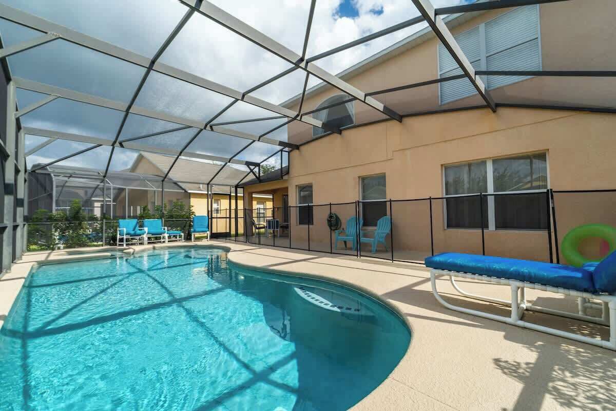 A swimming pool with a glass ceiling, blue lounge chairs, and a sunbed.