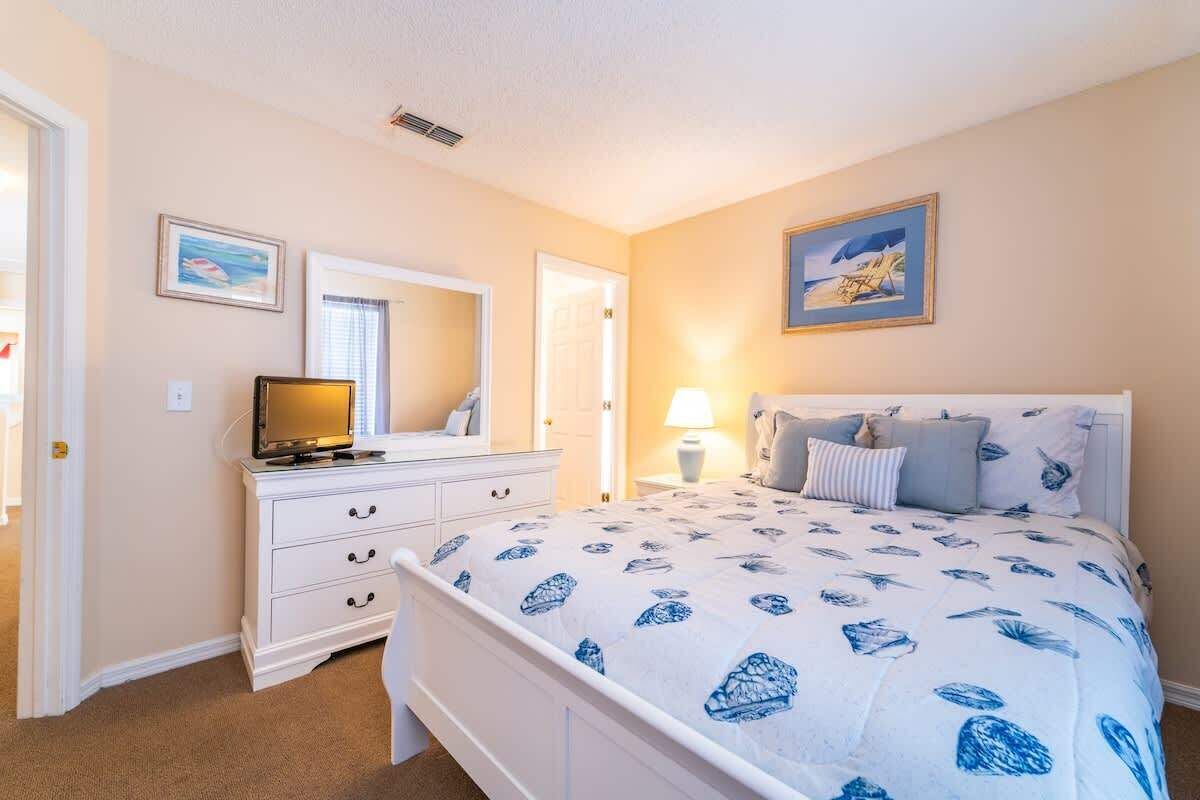 A bedroom with a bed, dresser, and a television.
