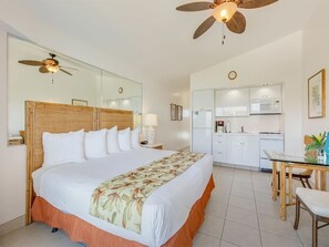 A hotel room with a large bed, a ceiling fan, a kitchen area with a microwave, and a dining table. - Beachy Penthouse w/Epic Ocean View, Free WiFi, Kitchenette–Waikīkī Shore PH03 (HONOLULU)