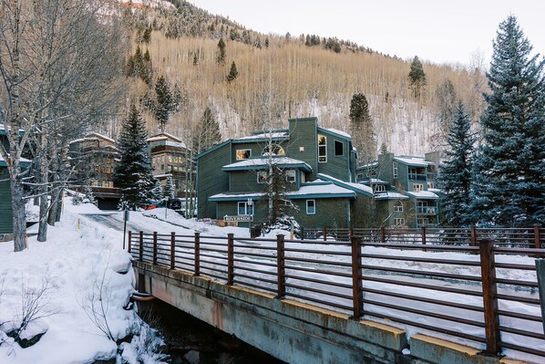 A snow-covered bridge leading to a multi-story building with a sign reading 'RIVERSID.'