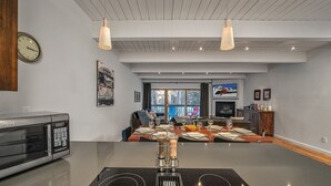 A modern kitchen with a built-in oven, a dining area with a wooden table set for six, and a large window overlooking a snowy landscape. - Riverside C03 A Mountain Forest Hideaway - 2 Bedrooms, 2 Bathrooms, Sleeps 6 (Telluride)