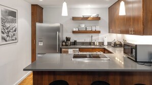 A modern kitchen with a stainless steel refrigerator, wooden cabinets, and a central island with stools. - Riverside C03 A Mountain Forest Hideaway - 2 Bedrooms, 2 Bathrooms, Sleeps 6 (Telluride)