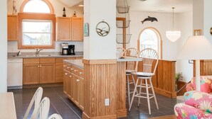 A kitchen with wooden cabinets, a dining area with chairs, and a chandelier.