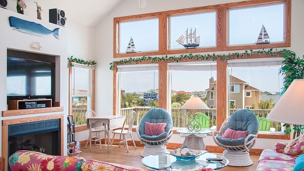 A spacious living room with a large TV, two comfortable chairs, a sofa, and a fireplace.