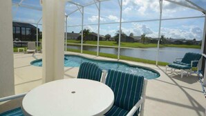 A covered outdoor pool area with a view of a lake and houses in the background.