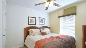 A bedroom with a bed, a ceiling fan, a window with blinds, and two framed pictures on the wall. - Waterfront Pool Townhome in Encantada Resort | Minutes to Disney (Kissimmee)