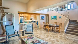 A spacious living area with a dining table, chairs, and a cat tree. There is a staircase leading to an upper level. - Borrego Springs Home w/ Desert & Mountain Views! (Borrego Springs)