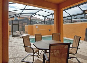 Uma área de piscina interna com mesa e cadeiras, um sinal de segurança e vista para o exterior.