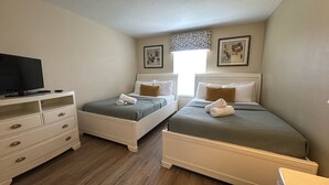Un dormitorio con dos camas, un televisor y un aparador.
