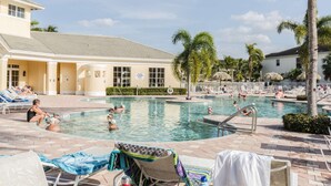 A swimming pool area with lounge chairs and a building with a sign indicating no lifeguards on duty.