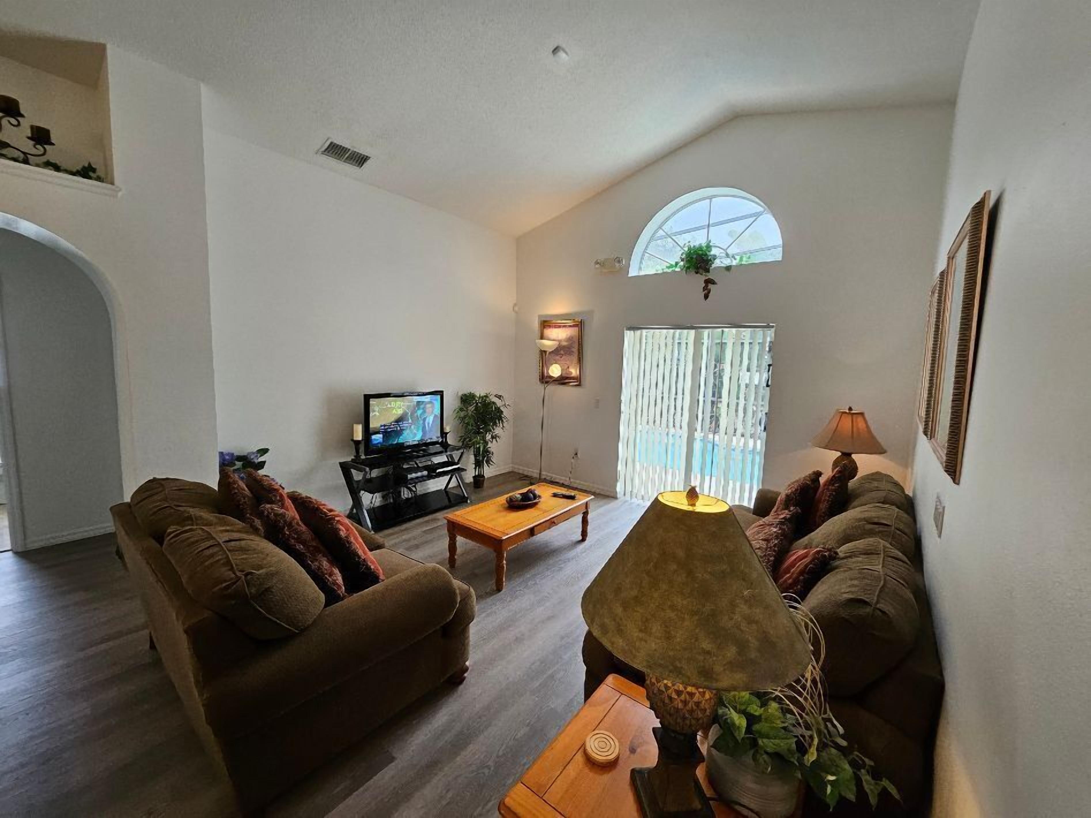 A cozy living room with a sofa, a coffee table, a TV, and a lamp.
