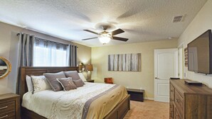 A bedroom with a bed, a ceiling fan, a dresser, a mirror, and a television. - Paradise Palms | 2 King Beds | Private Splash Pool & BBQ | Dog Friendly (Kissimmee)