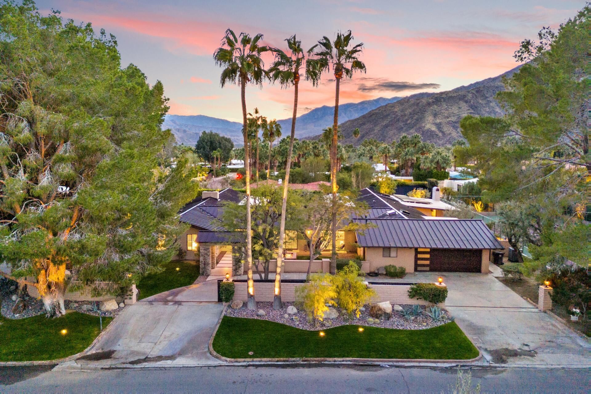 A residential area with multiple houses, palm trees, and a mountainous backdrop.
